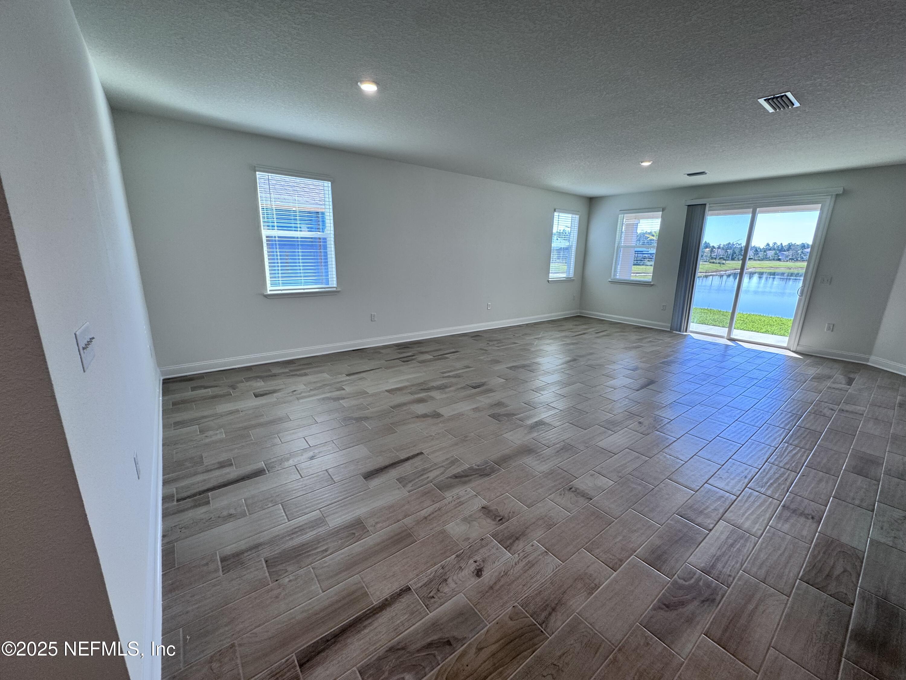11156 Spg Mdws Road Jacksonville, FL 32222 - Photo 6 of 33 an empty room with wooden floor and windows