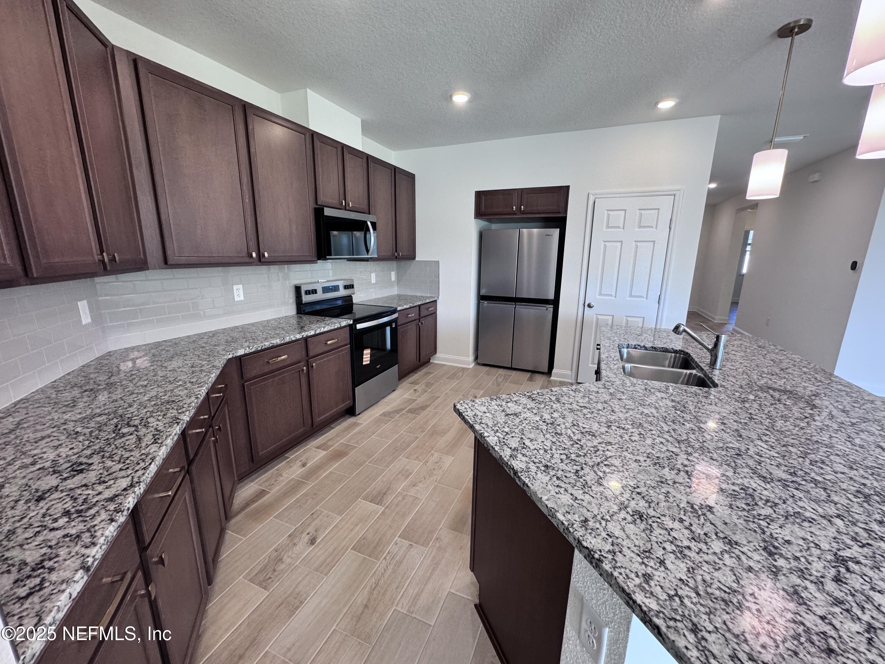 11156 Spg Mdws Road Jacksonville, FL 32222 - Photo 9 of 33 a kitchen with kitchen island granite countertop wooden cabinets a refrigerator and a sink