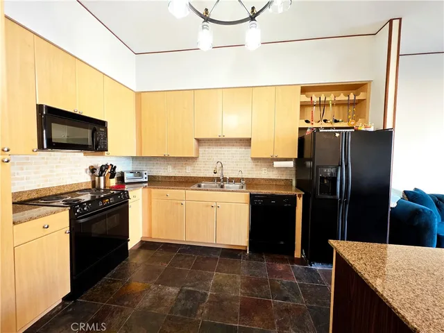 a kitchen with granite countertop a refrigerator a stove top oven a sink and cabinets
