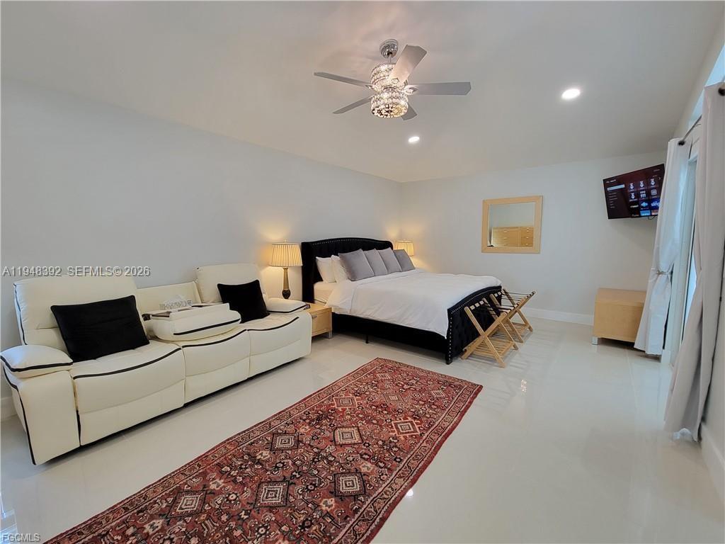237 Southwest 47th Street Cape Coral, FL 33914 - Photo 19 of 50 a spacious bedroom with a bed a couch and a chandelier