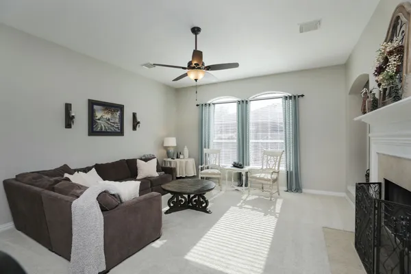 a living room with furniture a fireplace and a ceiling fan