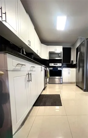 a kitchen with stainless steel appliances kitchen island granite countertop a refrigerator and a sink