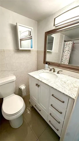 a bathroom with a granite countertop toilet sink and mirror