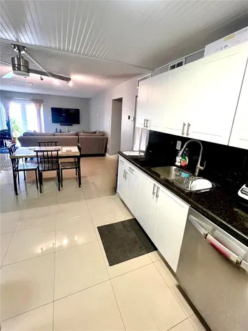 a living room with stainless steel appliances furniture a rug and a kitchen view