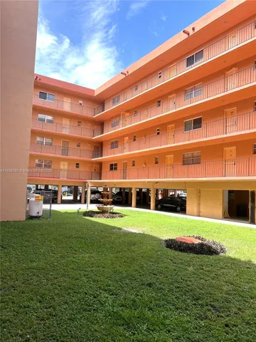 a view of a big building with a big yard and large trees