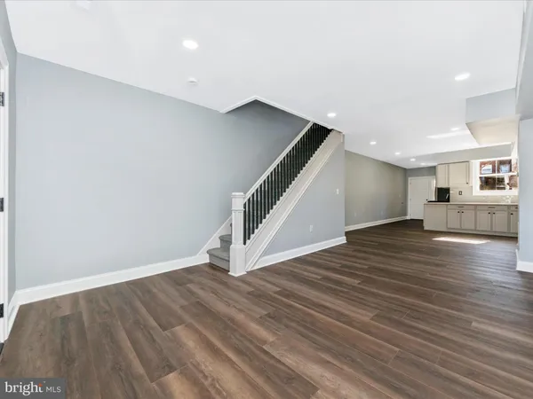 a view of an empty room with wooden floor and staircase