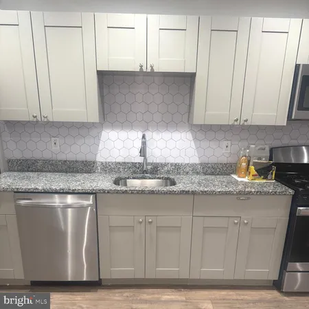a kitchen with granite countertop a sink a stove and cabinets