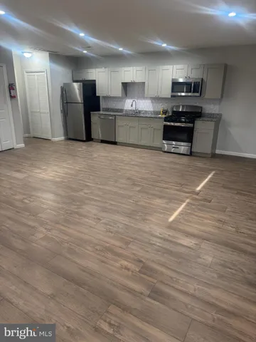 a large kitchen with stainless steel appliances a large counter top a stove and a sink