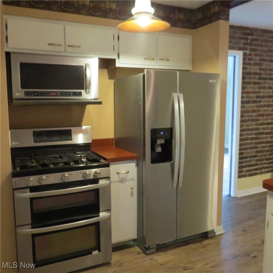 430 High Meadow Road Amherst, OH 44001 - Photo 5 of 29 Kitchen featuring brick wall, appliances with stainless steel finishes, and white cabinetry