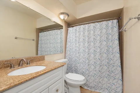 a bathroom with a granite countertop sink a toilet and a mirror