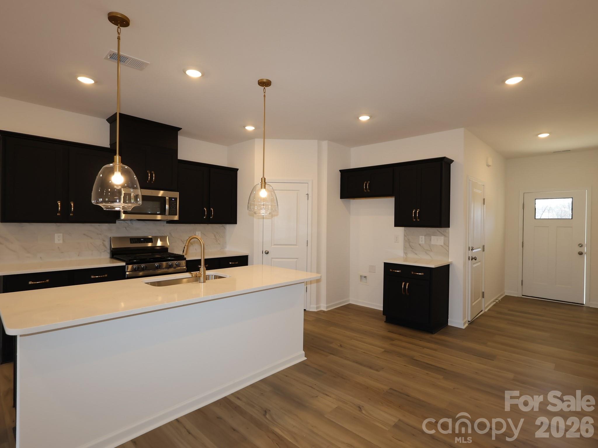 1152 Overbrook Place Wingate, NC 28174 - Photo 2 of 19 a large kitchen with stainless steel appliances a large counter top a stove a sink a refrigerator and a wooden floor