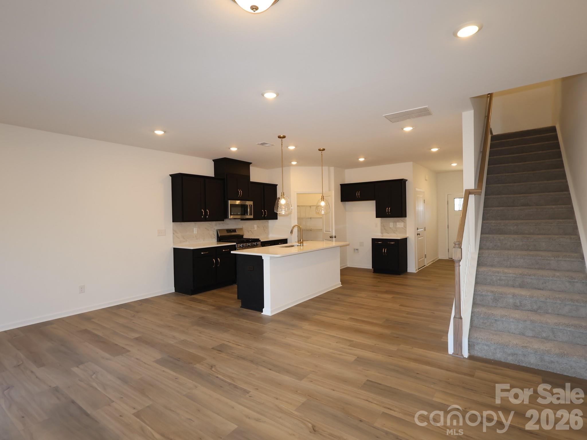 1152 Overbrook Place Wingate, NC 28174 - Photo 5 of 19 a large kitchen with stainless steel appliances kitchen island granite countertop a stove top oven and sink