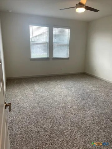 an empty room with a window and a fan