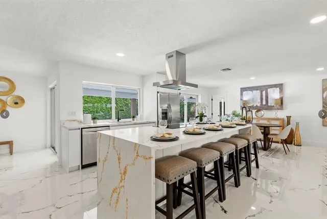 a dining room with stainless steel appliances kitchen island granite countertop a table and chairs in it