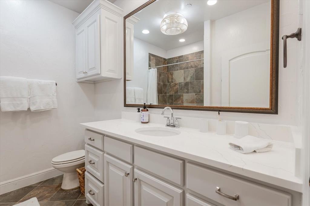 1653 Scenic Drive, Unit 102 Graford, TX 76449 - Photo 22 of 40 a bathroom with a toilet a sink and mirror