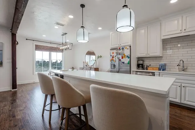 a kitchen with stainless steel appliances granite countertop a sink dishwasher a refrigerator with wooden cabinets and floor