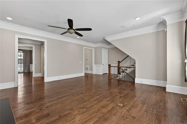 a view of an empty room with wooden floor and a ceiling fan