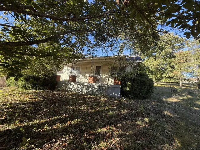 a backyard of a house with table and chairs under an umbrella
