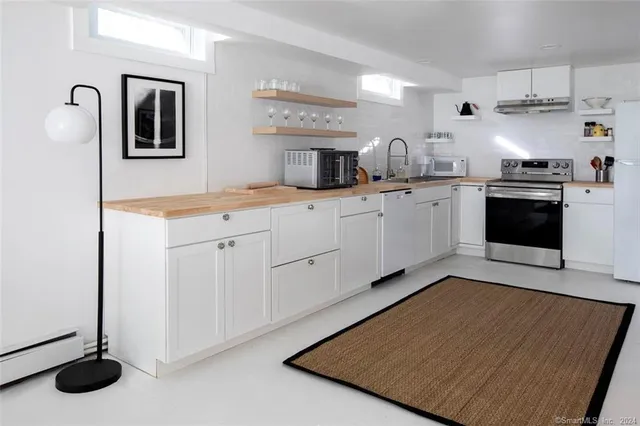 a kitchen with stainless steel appliances granite countertop a sink dishwasher stove and white cabinets