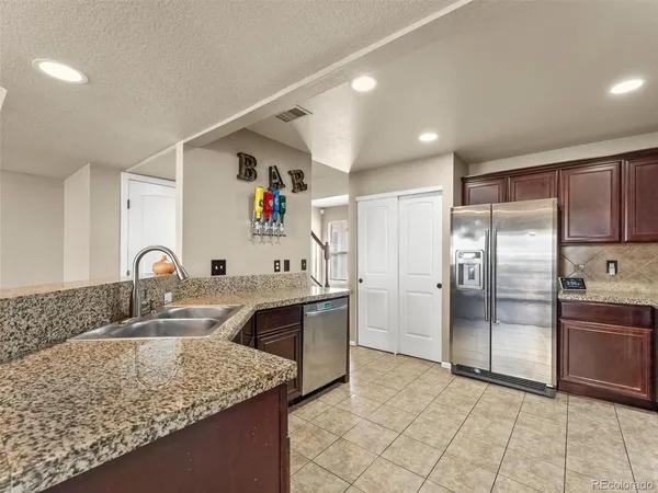 a kitchen with stainless steel appliances granite countertop a sink and a refrigerator