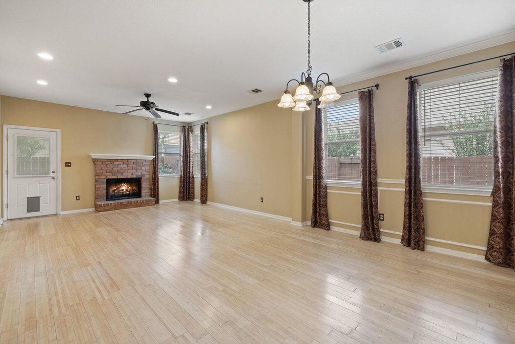 347 Spring Drive Kyle, TX 78640 - Photo 16 of 40 Luminous living space featuring polished hardwood floors and a cozy brick fireplace.