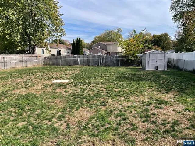 a backyard of a house with plants and large trees