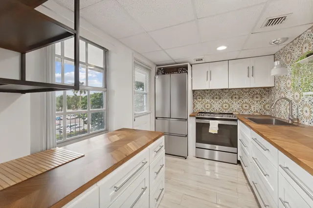 a kitchen with kitchen island a counter top space a sink stainless steel appliances and cabinets