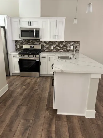 a kitchen with stainless steel appliances granite countertop a stove a sink and a microwave