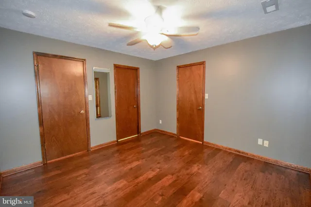 an empty room with wooden floor and a ceiling fan