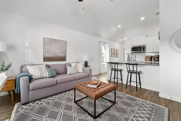 a living room with furniture a kitchen view and a dining table