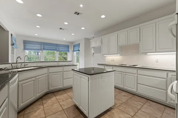 a kitchen with granite countertop white cabinets and white stainless steel appliances