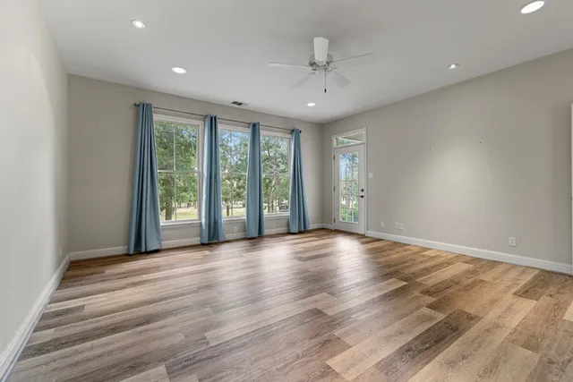 a view of an empty room with a window and wooden floor