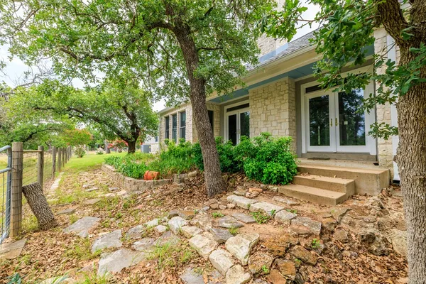 a view of a house with a small yard and large tree