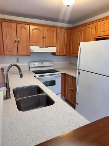 a kitchen with a sink a refrigerator and cabinets