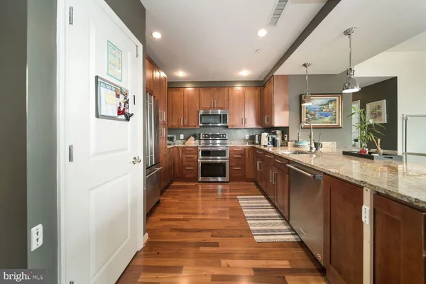 a large kitchen with stainless steel appliances kitchen island a large counter top a stove and a sink
