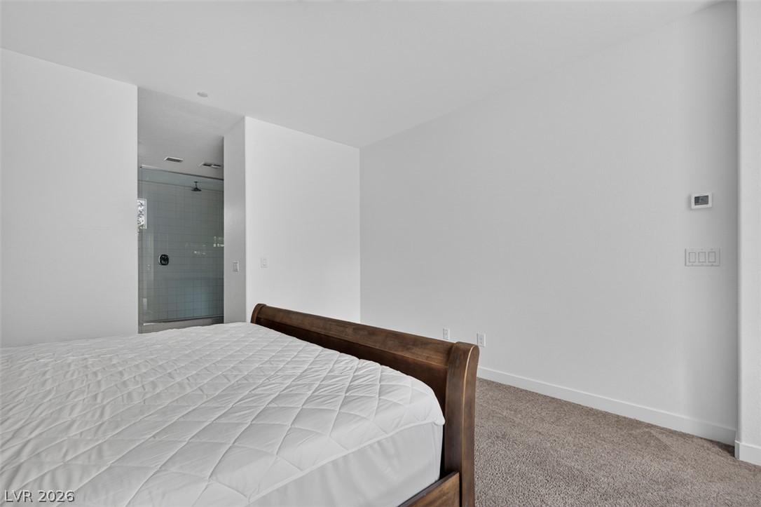 1100 East Sunset Road Henderson, NV 89011 - Photo 17 of 58 A tranquil bedroom retreat features plush carpet and an adjacent walk-in shower.