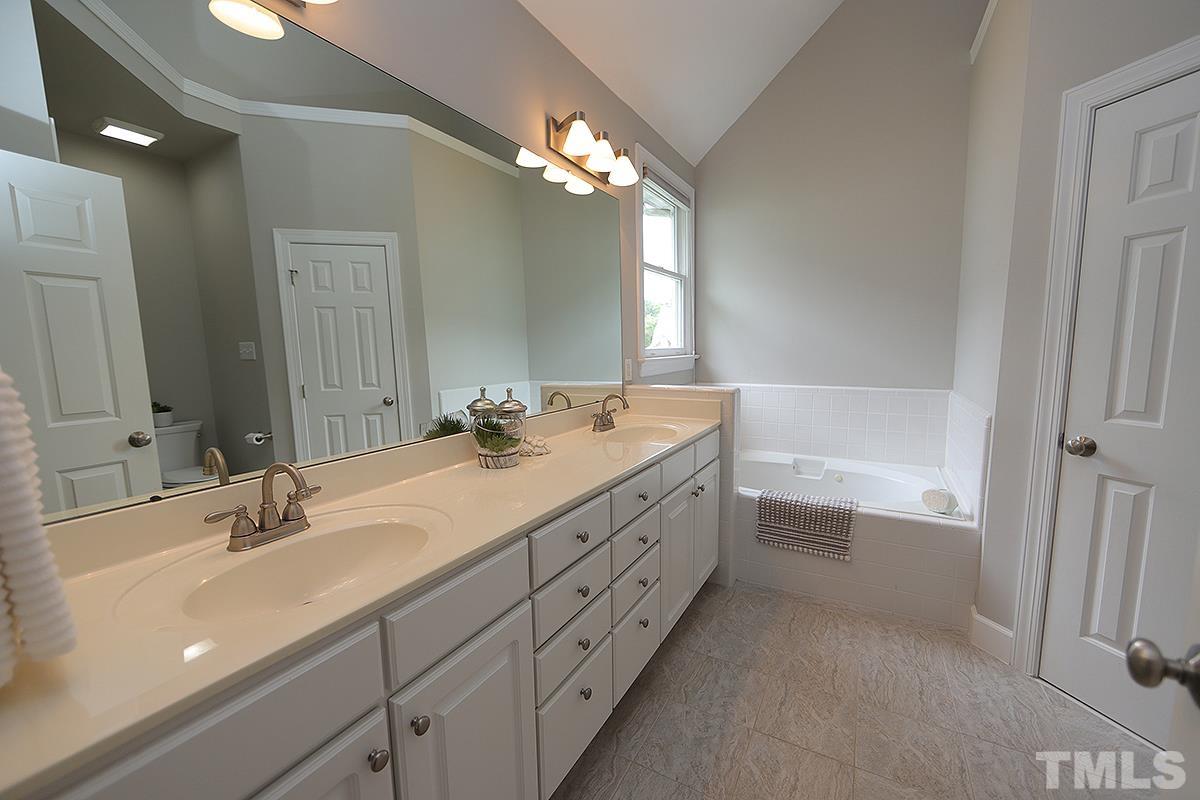 6317 Belle Crest Drive Raleigh, NC 27612 - Photo 14 of 29 a bathroom with a double vanity sink a mirror and a bathtub