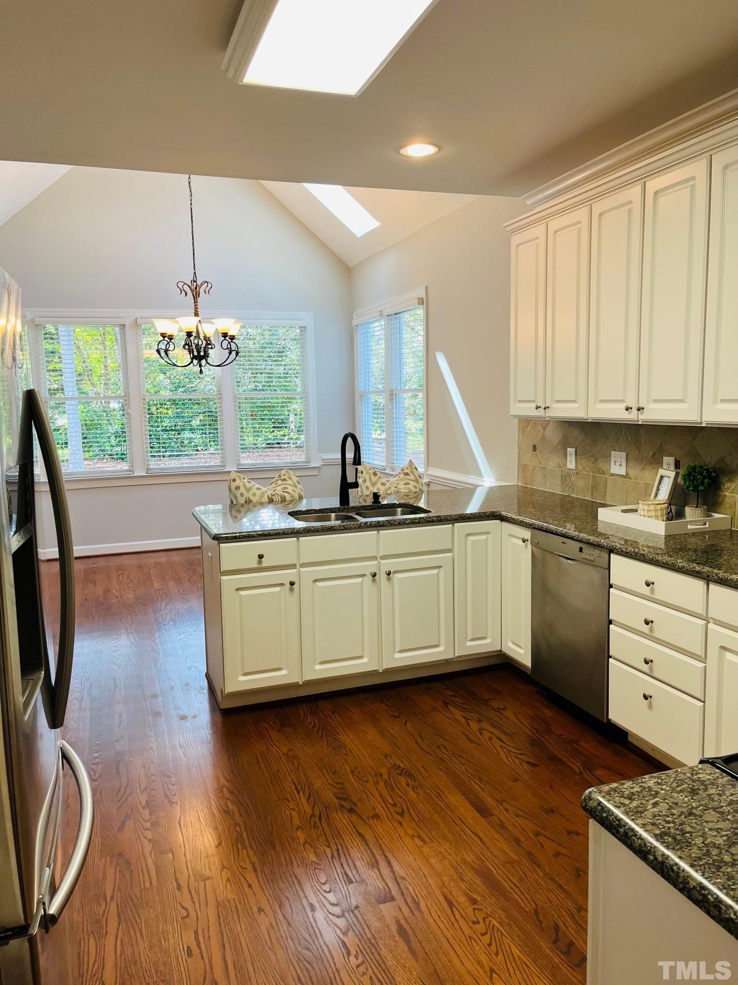 6317 Belle Crest Drive Raleigh, NC 27612 - Photo 8 of 29 a kitchen with kitchen island granite countertop a stove a sink a center island and wooden floor