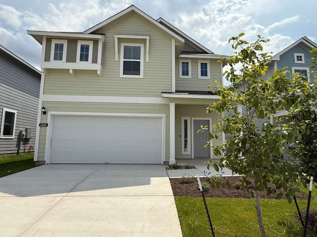 Traditional-style home featuring driveway, a garage, and a porch