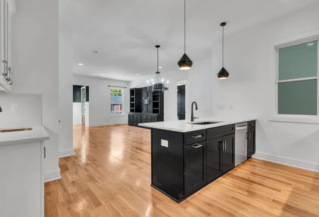 a kitchen with stainless steel appliances granite countertop a sink a stove and a wooden floors