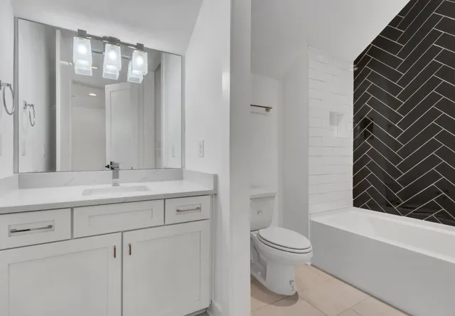 a bathroom with a granite countertop sink toilet a mirror and bathtub