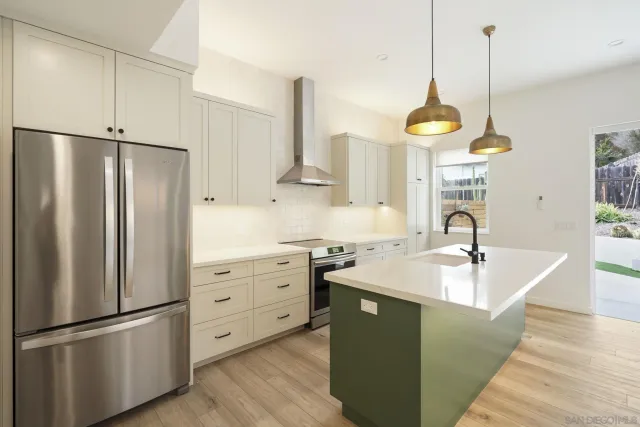 a kitchen with stainless steel appliances granite countertop a sink a refrigerator and a wooden floor