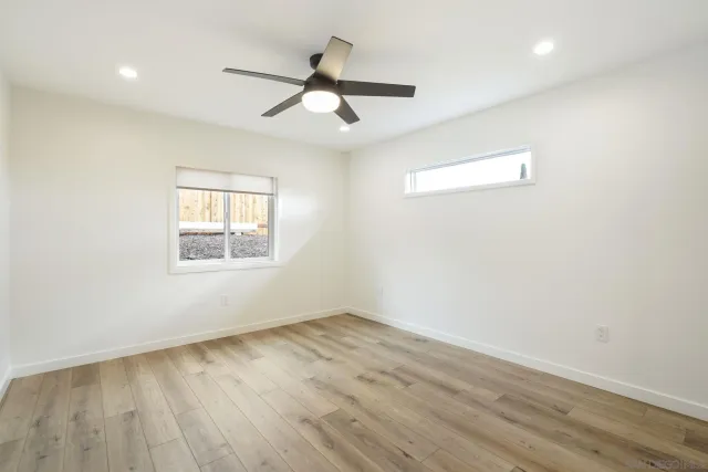 an empty room with wooden floor fan and windows