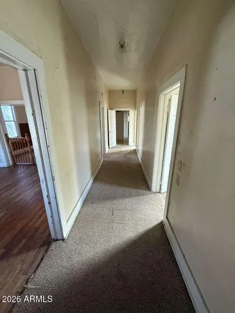 a view of a hallway to a livingroom with wooden floor and stairs