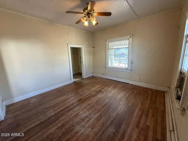 a view of an empty room with wooden floor and a window