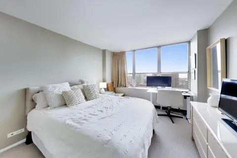 a bedroom with a bed a computer on desk and a chair