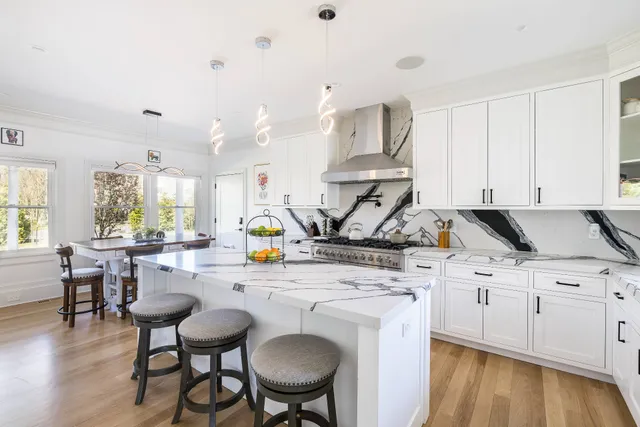 a kitchen with stainless steel appliances kitchen island a white table chairs and a wooden floor