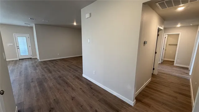 a view of an empty room with window and wooden floor