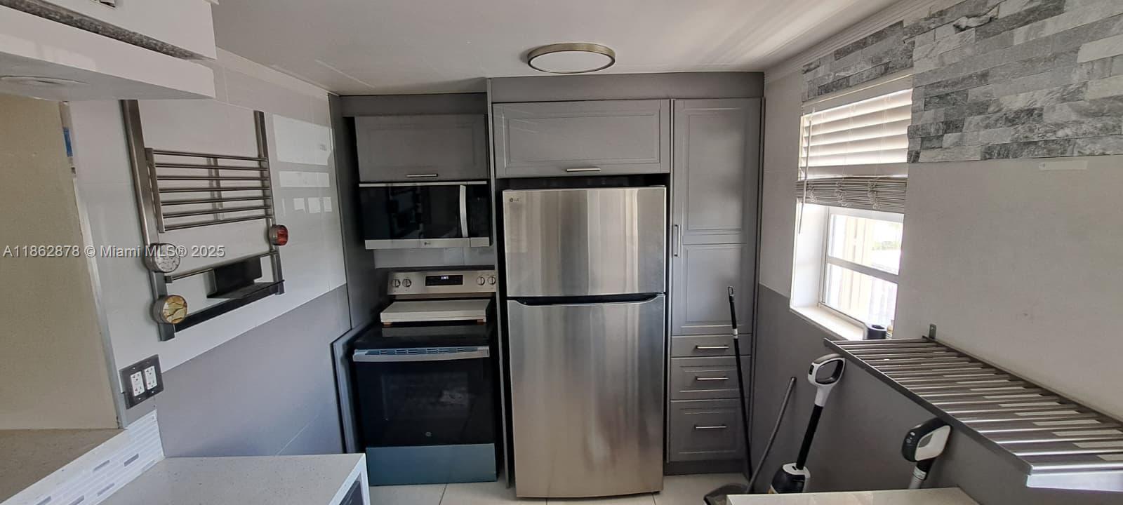 14180 Southwest 84th Street, Unit 203G Miami, FL 33183 - Photo 2 of 17 a kitchen with a refrigerator and a stove top oven