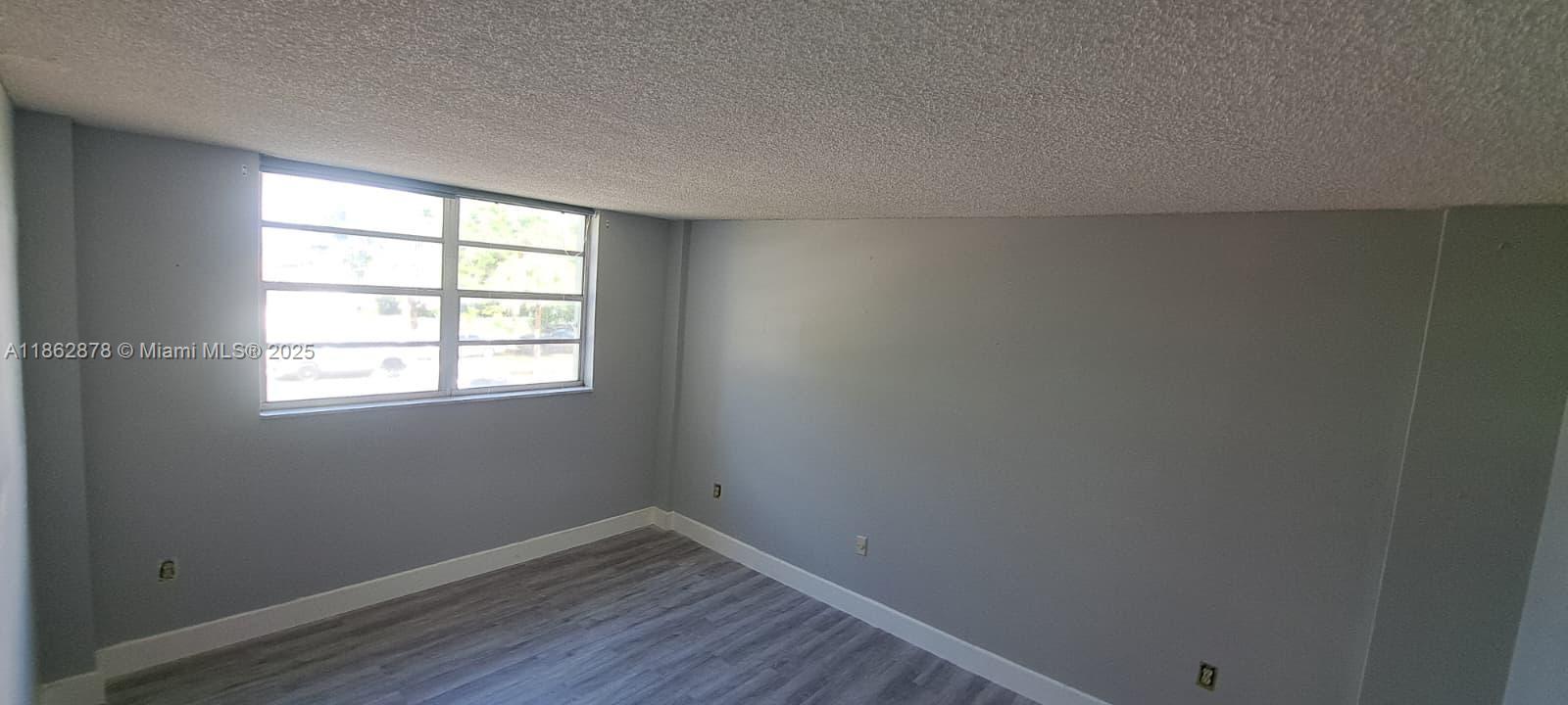 14180 Southwest 84th Street, Unit 203G Miami, FL 33183 - Photo 9 of 17 an empty room with wooden floor and windows